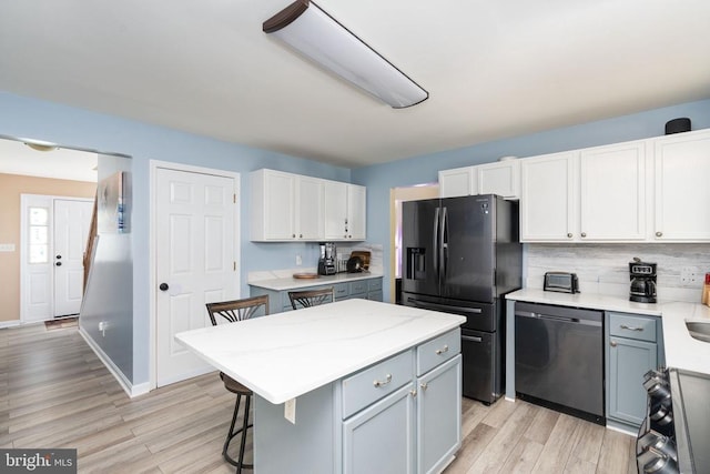 12107 Knight Ct, Fredericksburg, VA 22407 - kitchen with stainless steel dishwasher, black fridge, backsplash, light wood-type flooring, and a breakfast bar