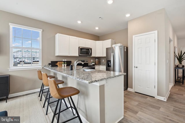 115 Rae Ct, Luray, VA 22835 - kitchen featuring appliances with stainless steel finishes, white cabinetry, light stone countertops, a peninsula, and light wood finished floors