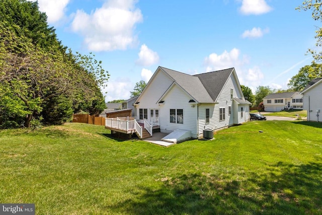 rear view of property featuring a lawn, a shingled roof, a wooden deck, and central AC