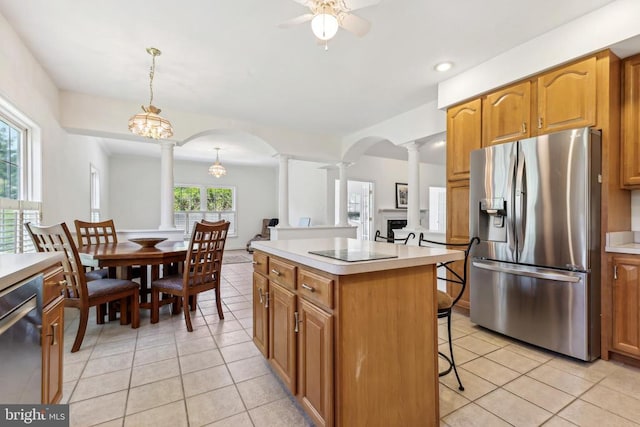 kitchen with light tile patterned flooring, appliances with stainless steel finishes, decorative columns, and arched walkways