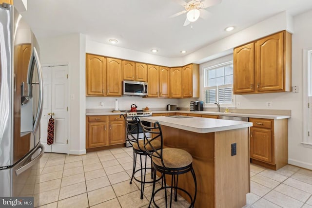 kitchen featuring a center island, light tile patterned floors, stainless steel appliances, and a kitchen bar