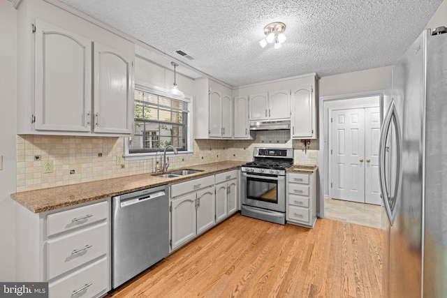 47 Marwood Dr, Palmyra, VA 22963 - kitchen featuring appliances with stainless steel finishes, under cabinet range hood, a textured ceiling, light wood-type flooring, and backsplash