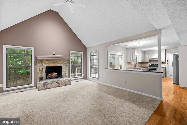 47 Marwood Dr, Palmyra, VA 22963 - unfurnished living room featuring a textured ceiling, a ceiling fan, a stone fireplace, light wood-style floors, and high vaulted ceiling