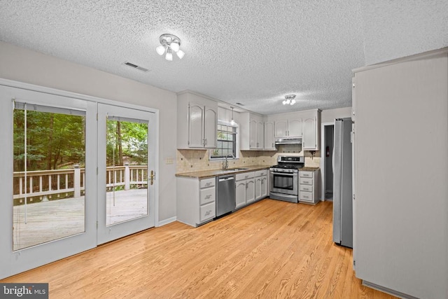 47 Marwood Dr, Palmyra, VA 22963 - kitchen with stainless steel appliances, light wood-style flooring, under cabinet range hood, a textured ceiling, and backsplash
