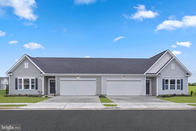 traditional-style house featuring driveway, a front yard, roof with shingles, and an attached garage