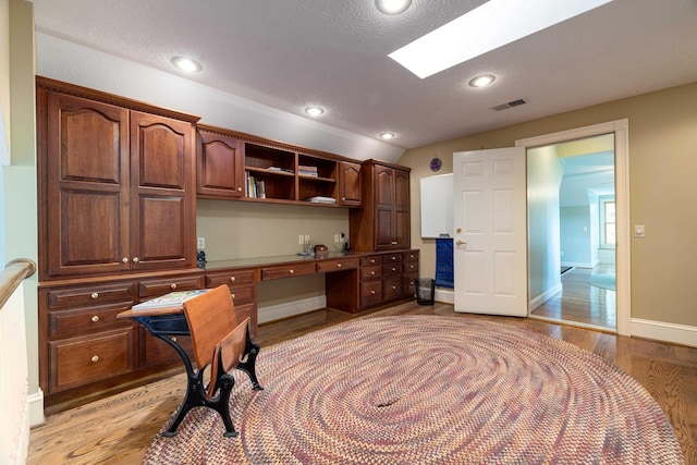 5090 Springhouse Cir, Rockingham, VA 22802 - office space with built in desk, light wood-type flooring, visible vents, and lofted ceiling with skylight