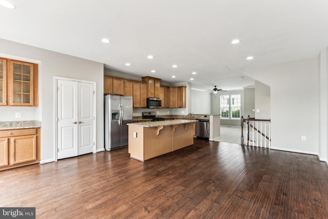 3107 Alliance Ct, Fredericksburg, VA 22408 - kitchen with appliances with stainless steel finishes, a breakfast bar area, a center island, brown cabinetry, and dark wood-type flooring