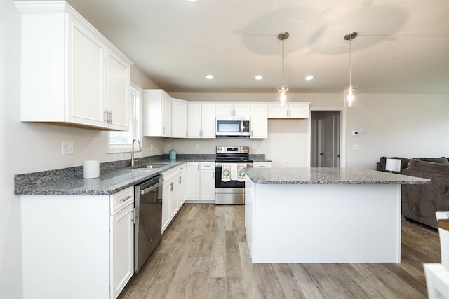 kitchen with stainless steel appliances, white cabinetry, sink, and pendant lighting