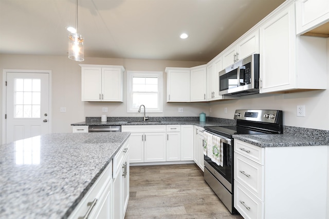 kitchen featuring sink, white cabinetry, dark stone countertops, stainless steel appliances, and light hardwood / wood-style floors