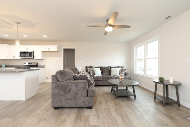 living room with light hardwood / wood-style flooring and ceiling fan