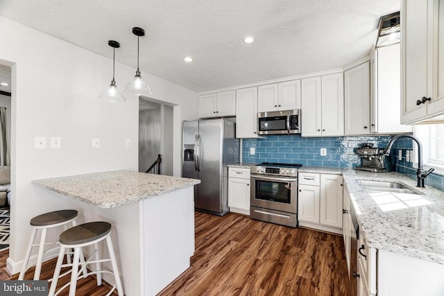  - kitchen with stainless steel appliances, backsplash, dark wood-style flooring, light stone countertops, and white cabinetry