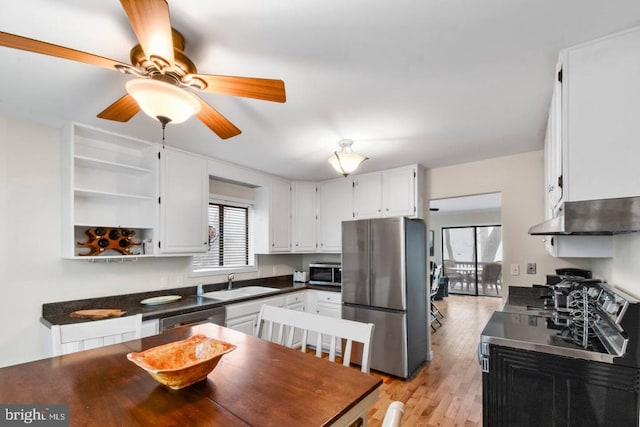 kitchen featuring dark countertops, appliances with stainless steel finishes, white cabinets, and a sink