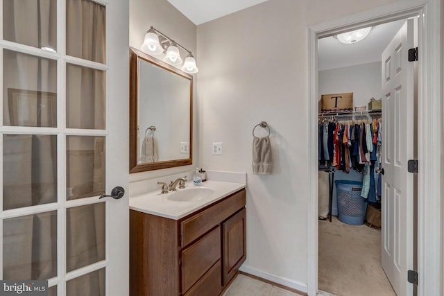  - bathroom featuring vanity, a spacious closet, and baseboards