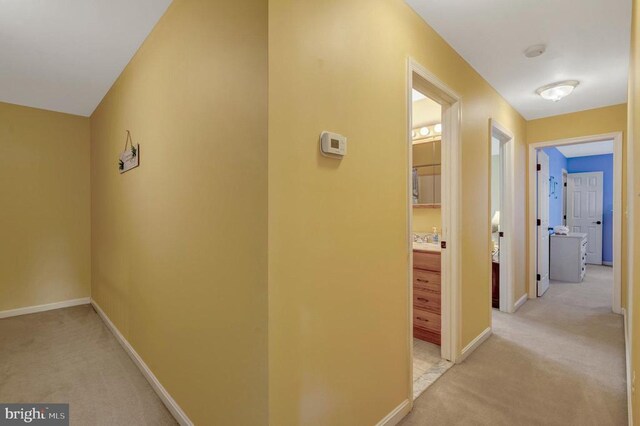  - hall featuring light colored carpet and baseboards
