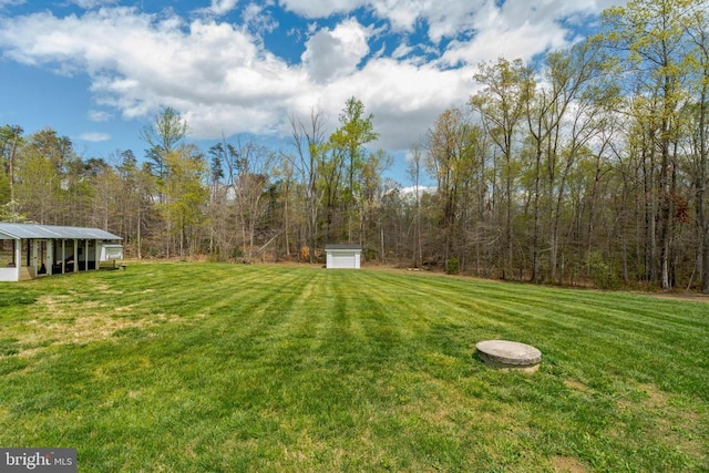  - view of green lawn with an outdoor structure and a forest view