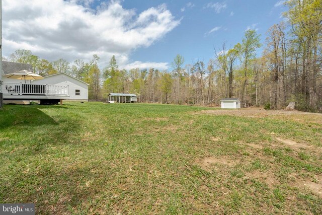  - view of grassy yard with an outdoor structure and a wooden deck