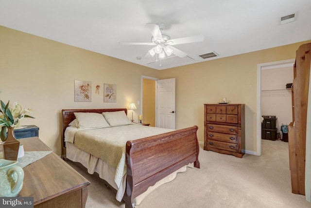  - bedroom with light colored carpet, a walk in closet, a closet, a ceiling fan, and baseboards