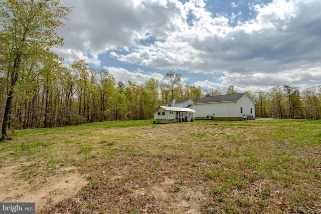  - view of grassy yard featuring an outdoor structure, a view of trees, and a storage unit