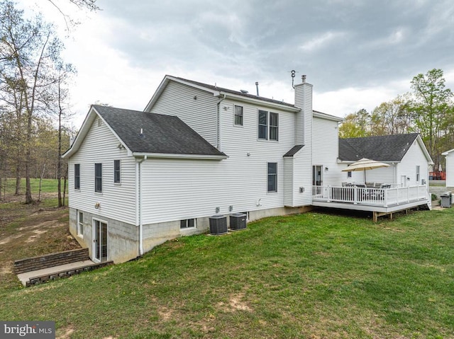  - rear view of house featuring a chimney, a deck, a yard, and a shingled roof