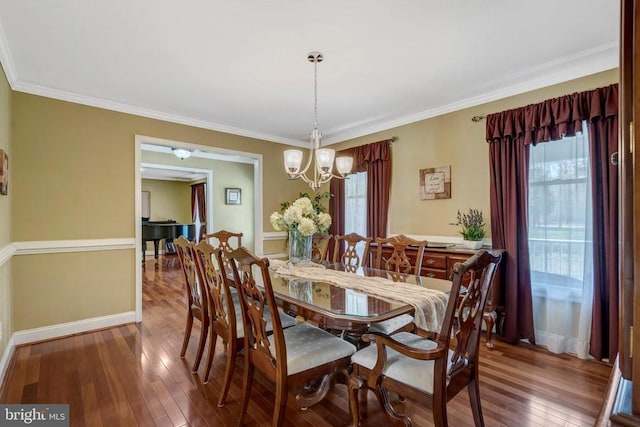  - dining room with wood-type flooring, a chandelier, crown molding, and baseboards
