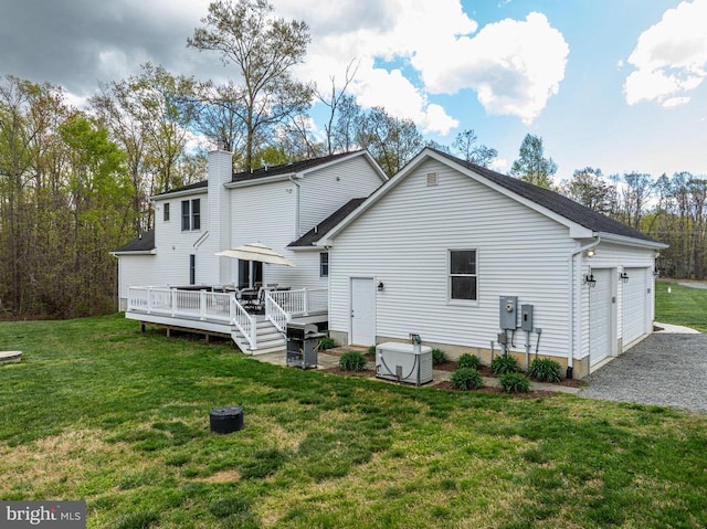  - rear view of house featuring a garage, a wooden deck, a lawn, and a chimney