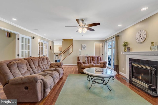  - living room featuring stairs, a tiled fireplace, recessed lighting, a ceiling fan, and wood finished floors