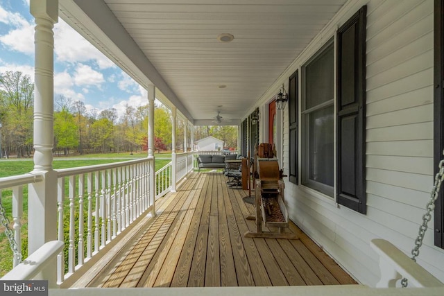  - wooden deck with covered porch and view of scattered trees