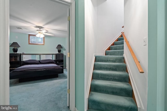  - staircase featuring a ceiling fan and carpet flooring