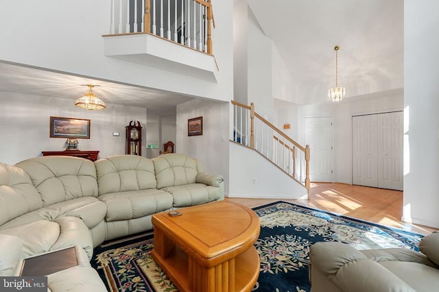  - living room featuring a chandelier, a high ceiling, stairs, wood finished floors, and baseboards