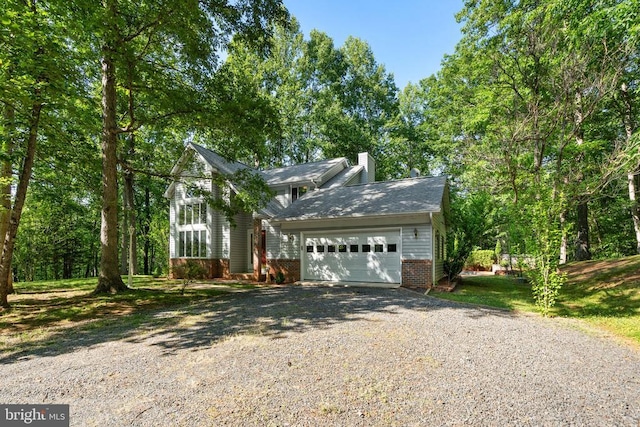  - traditional-style home with driveway, a chimney, an attached garage, and brick siding