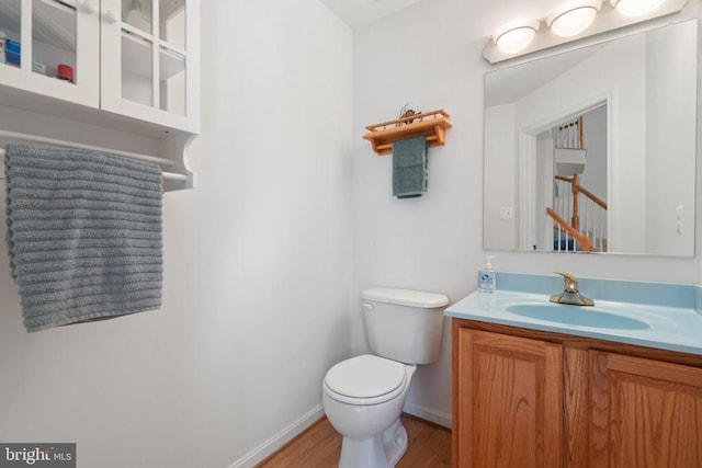  - bathroom with toilet, vanity, wood finished floors, and baseboards