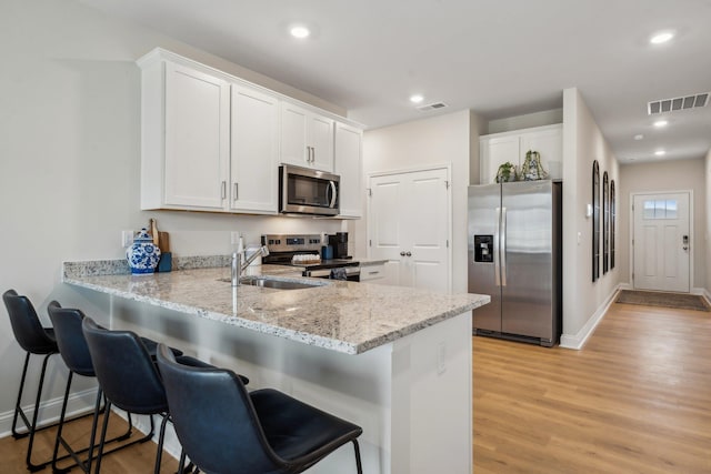 14767 Green View Dr, Elkton, VA 22827 - kitchen with a peninsula, light wood finished floors, a sink, stainless steel appliances, and visible vents