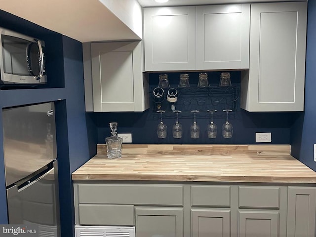  - kitchen featuring butcher block counters, stainless steel appliances, and white cabinetry