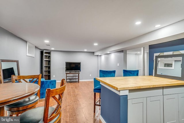  - kitchen featuring butcher block countertops, open floor plan, light wood finished floors, recessed lighting, and a breakfast bar area