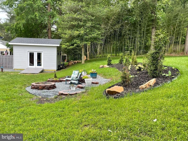  - view of green lawn with an outdoor fire pit, french doors, and an outbuilding