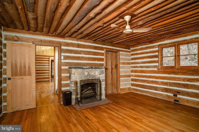 unfurnished living room with wooden ceiling, wooden walls, hardwood / wood-style flooring, ceiling fan, and a fireplace