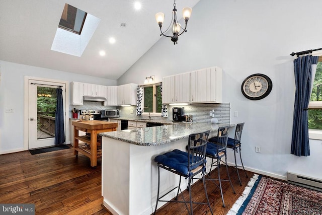 589 Pedlars Edge Dr, Roseland, VA 22967 - kitchen featuring a peninsula, a baseboard heating unit, under cabinet range hood, high vaulted ceiling, and a skylight