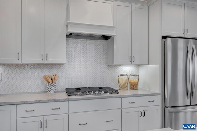kitchen featuring backsplash, stainless steel appliances, white cabinetry, and custom range hood