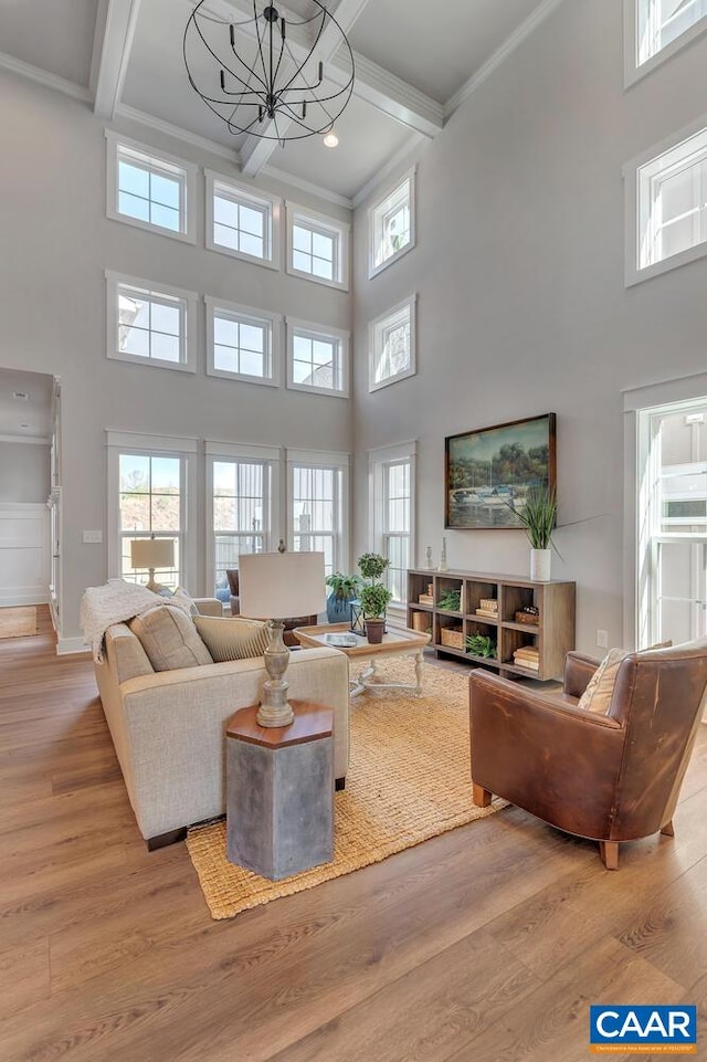living area with beam ceiling, wood finished floors, ornamental molding, coffered ceiling, and a high ceiling