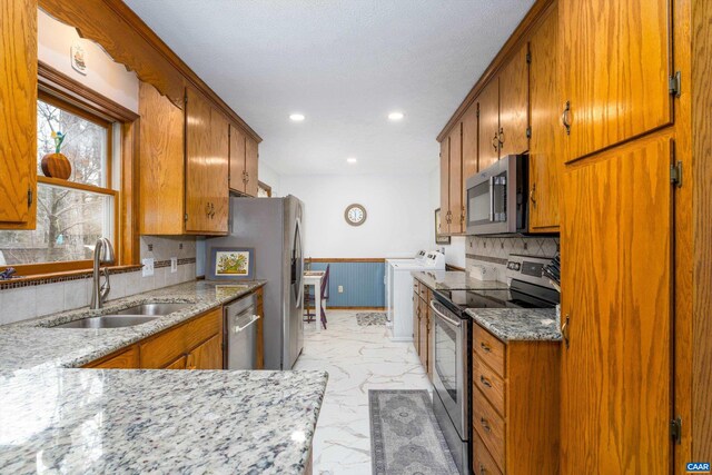 609 Jefferson Dr, Palmyra, VA 22963 - kitchen with a sink, washer / dryer, brown cabinets, marble finish floor, and appliances with stainless steel finishes
