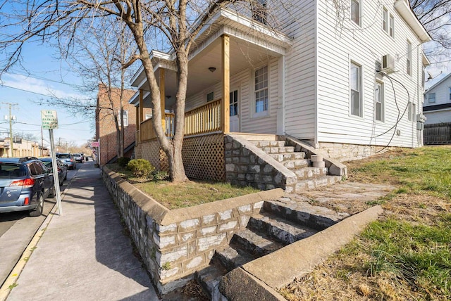 view of side of property featuring covered porch, stairs, and cooling unit
