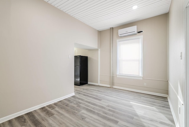 empty room featuring baseboards, light wood-style floors, and a wall mounted AC
