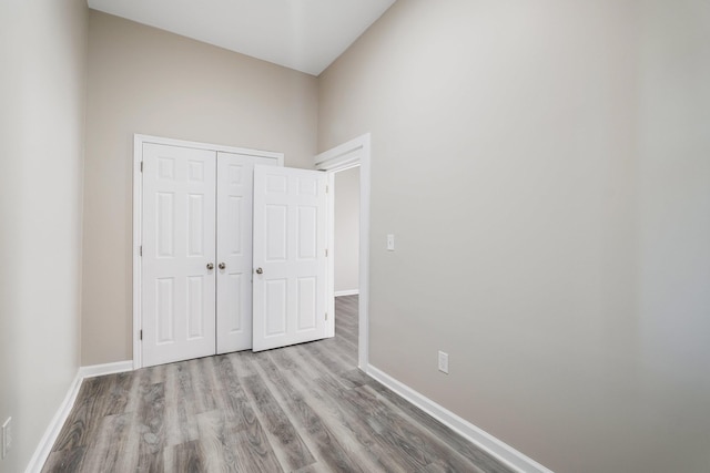 unfurnished bedroom with baseboards, a closet, and wood finished floors