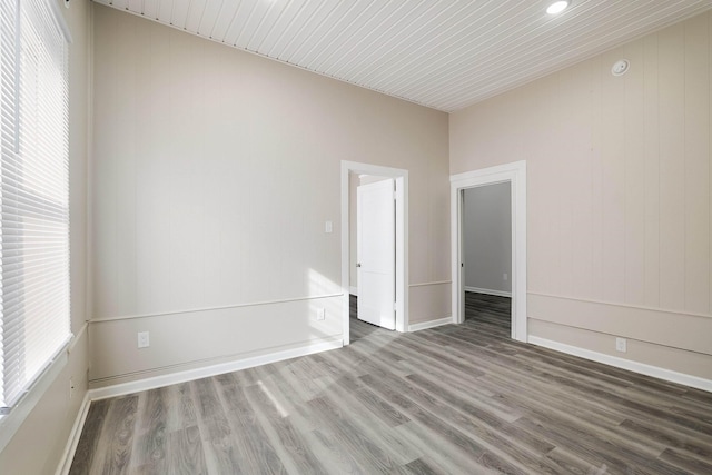 unfurnished room featuring baseboards, plenty of natural light, and wood finished floors