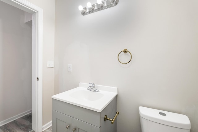 bathroom with toilet, vanity, and wood finished floors