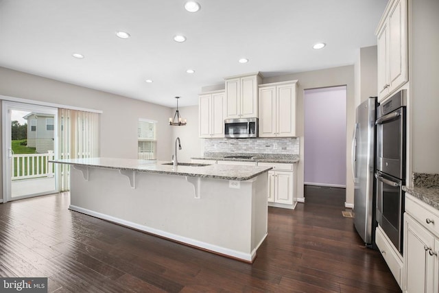 6056 Greenspring Rd, Fredericksburg, VA 22407 - kitchen featuring appliances with stainless steel finishes, a breakfast bar, recessed lighting, tasteful backsplash, and a sink