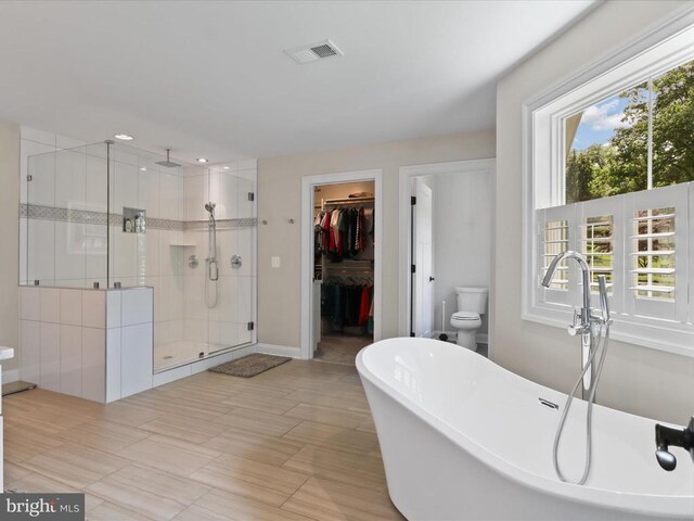 full bathroom with a shower stall, a freestanding tub, a spacious closet, and recessed lighting