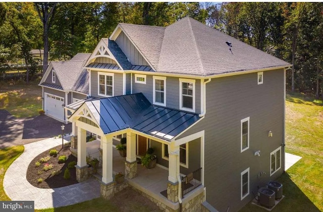 back of property featuring a standing seam roof, a porch, metal roof, and driveway