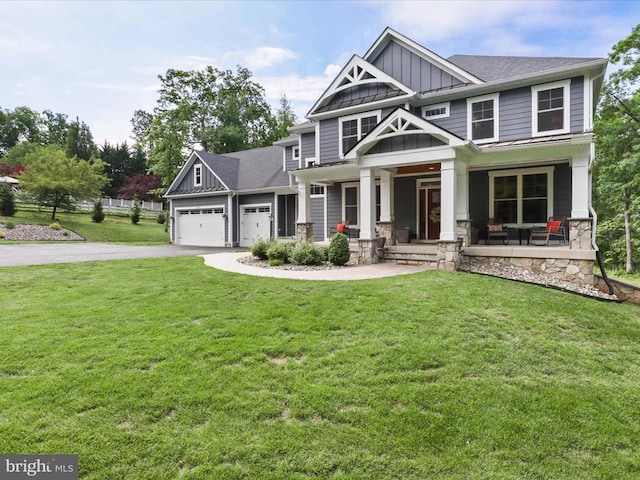 craftsman-style home with board and batten siding, covered porch, driveway, and a front lawn