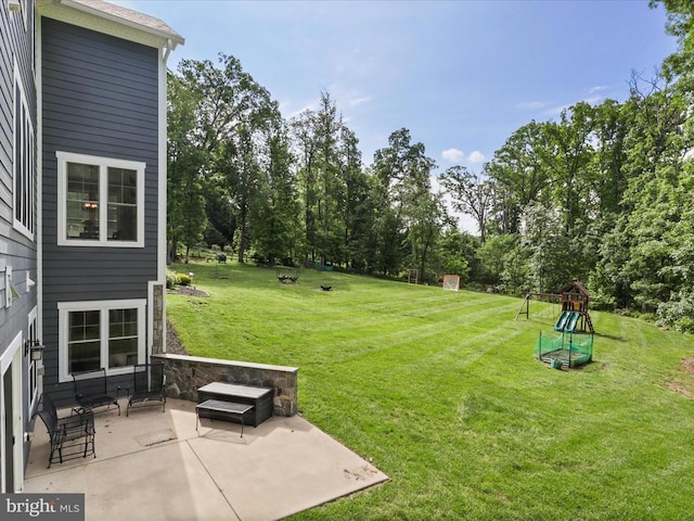 view of grassy yard featuring a patio area and a playground